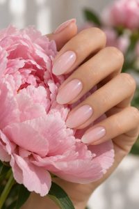 Sheer milky ballet pink almond nails holding a pink peony